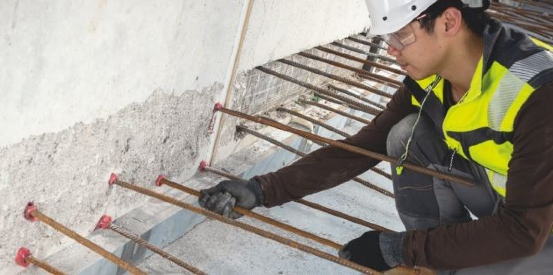 Jobsite worker inserting rebar into hole filled with RE100 chemical mortar