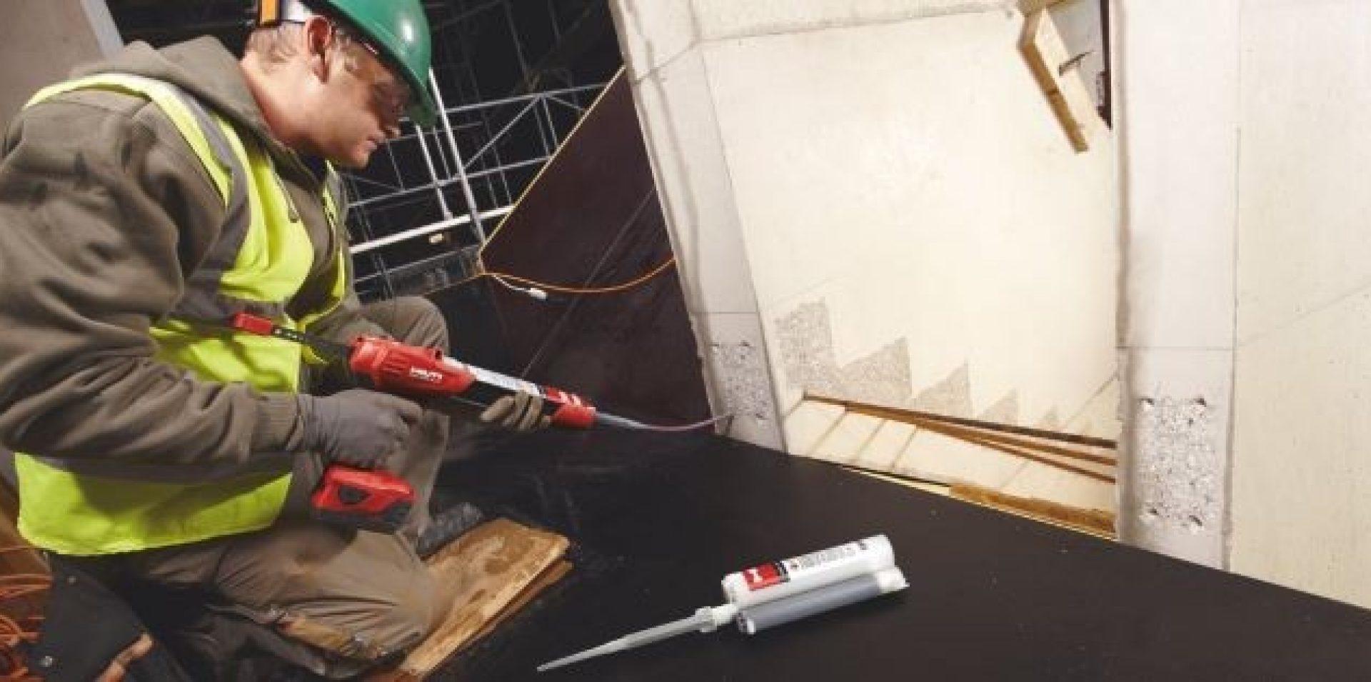 Jobsite worker inserting chemical mortar for staircase rebaring.